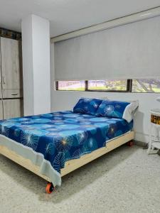 a bedroom with a bed with blue sheets and a window at Cali Sur Centrar Apto 2 - Somos Pet Friendly in Cali