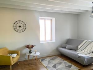 a living room with a couch and a clock on the wall at Bienvenue dans le Beaujolais in Le Perréon