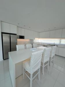 a kitchen with a white table and white chairs at Serena Boutique Potrero Garay in Potrero de Garay