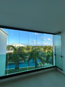 a room with a view of a pool and palm trees at Apartamento Iberostate Praia do Forte, 2 quartos in Mata de Sao Joao