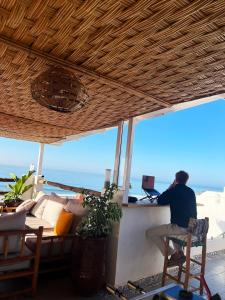 a man sitting at a desk in front of a computer at BigBlue Surf Experience Hostel in Taghazout