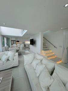 a living room with white couches and a staircase at Serena Boutique Potrero Garay in Potrero de Garay