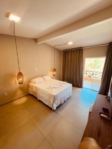 a bedroom with a bed and a large window at Pousada Villa Manzuá in Cascavel