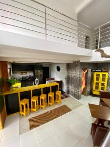 a living room with yellow stools and a kitchen at Casa Ampla na Brava in Itajaí