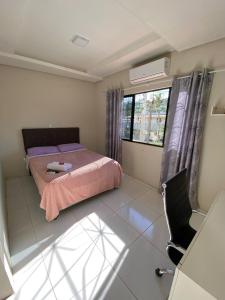 a bedroom with a bed and a chair and a window at Casa Ampla na Brava in Itajaí