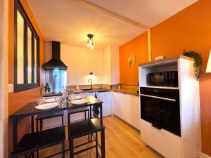 a kitchen with orange walls and a black and white refrigerator at Appartement Graulhet le nid de carivel in Graulhet