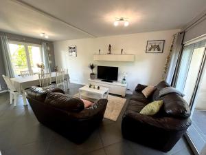 ein Wohnzimmer mit 2 Ledersofas und einem Tisch in der Unterkunft Family home between Paris and Disneyland in Noisy-le-Grand