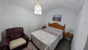 a bedroom with a bed and a chair at Cueva Rincón Bustamante in Gorafe
