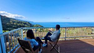a man and woman sitting on chairs on a balcony at Faria's House 2 in Feiteiras +4 photos