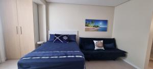 ein Schlafzimmer mit einem blauen Bett und einem Sofa in der Unterkunft Jk LOFT à beira-mar de CAPÃO DA CANOA, com ar condicionado split in Capão da Canoa