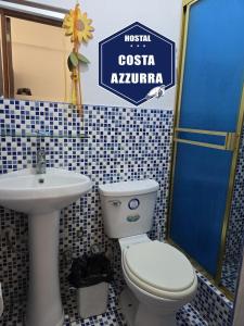 a bathroom with a toilet and a sink and a sign at Hostal COSTA AZZURRA in Cerro Azul