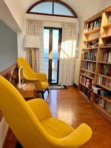 ein Wohnzimmer mit gelben Stühlen und Bücherregalen in der Unterkunft Villa Orea Elena-Mani-Kalamata in Verga Kalamata