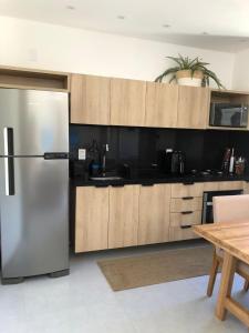 Una cocina con refrigerador de acero inoxidable y una mesa. en Essence - B004 - Milagres, en Porto de Pedras