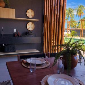 una mesa con platos y vasos y una planta en ella en Essence - B004 - Milagres, en Porto de Pedras