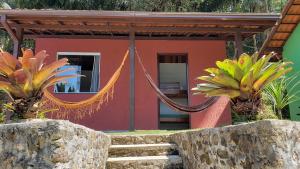 a house with a hammock in front of it at Pousada Beija Flor-Lumiar - Piscinas e Café in Lumiar