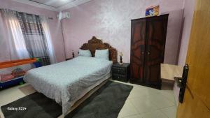 a bedroom with a large bed and a wooden dresser at Appartement B à 7min de l’aéroport de Marrakech in Marrakech