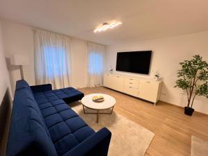 a living room with a blue couch and a tv at Designer Apartment in Sinsheim Erstbezug 75 TV mit Netflix und offene Küche WeHome Premium in Sinsheim