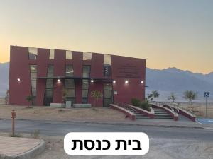 Beʼer Oraשלווה במדבר的一座红色的大建筑,前面有楼梯