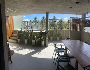 een terras met een houten tafel, stoelen en planten bij Casa Artur - Milagres in São Miguel dos Milagres
