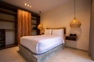 a bedroom with a large white bed and two pendant lights at Nook Tulum in Tulum +24 photos