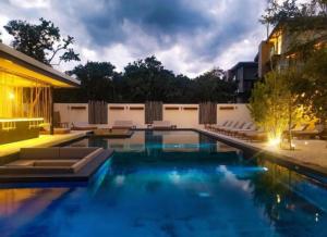a swimming pool with lounge chairs next to a building at Nook Tulum in Tulum
