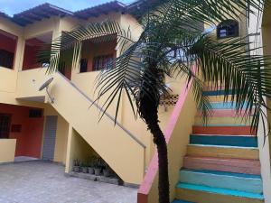 a palm tree in front of a building with a rainbow staircase at Eplantae - Cabo frio - RJ in Cabo Frio