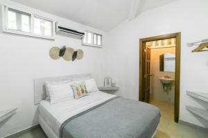 a white bedroom with a bed and a sink at Pineapple House in Bocas Town
