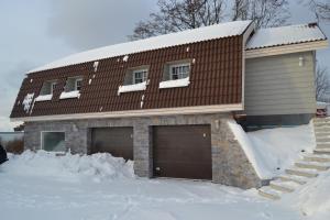 una casa con dos puertas de garaje en la nieve en Taimela Holiday Home with Sauna en Lohusalu