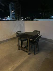 ein Tisch und zwei Stühle, die nachts auf einem Dach stehen in der Unterkunft Casa em Caraguatatuba 2 in Caraguatatuba