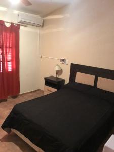 a bedroom with a black bed and a red curtain at El Bosque in San Marcos Sierras