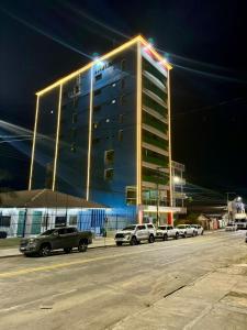 a large building with cars parked in a parking lot at Swamy Hotel in Cruzeiro do Sul