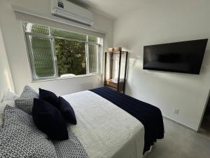 a bedroom with a bed and a tv on the wall at Studio Completo com Vista no Catete in Rio de Janeiro