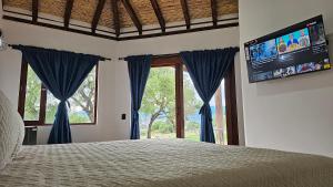 a bedroom with a bed with blue curtains and a tv at Cabañas Villa Celeste in Villa de Leyva