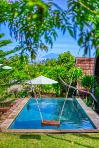 a swing by a swimming pool with an umbrella at DNR Lumbung Garden in Nusa Penida