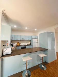 NarweeにあるLovely Modern Family home for your family and friendsの白いキャビネット付きのキッチン、カウンター(2つのスツール付)