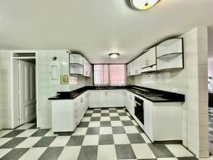 una cucina con mobili bianchi e pavimento a scacchi di Maljut House & Coffee a Cali