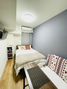 a small bedroom with two beds and a table at T-Hotel 浅草 in Tokyo