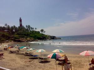 una playa con muchas sombrillas y gente en el agua en Luxury pool villa kovalam, en Trivandrum 6 fotos más