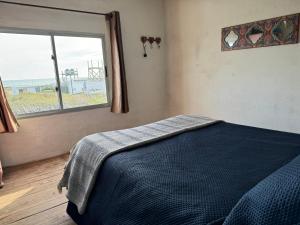 Un dormitorio con una cama y una ventana grande. en Sat Nam, en Cabo Polonio