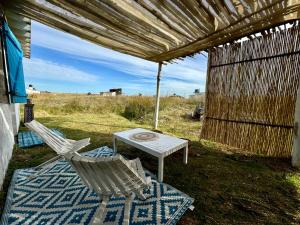 una mesa y dos sillas sentadas bajo una pérgola en Sat Nam, en Cabo Polonio