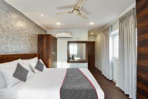 a bedroom with a bed with white sheets and a window at Super Collection O Manu in Bengaluru