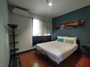 a bedroom with a white bed and a window at Baan Wangderm Hotel in Bangkok