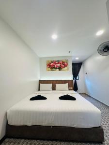a bedroom with a large white bed with black pillows at Ar Rayyan Hotel in Tanah Rata