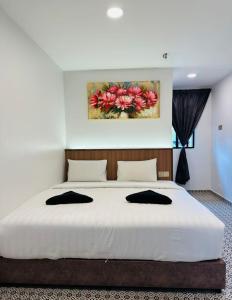 a bedroom with a large white bed with a painting on the wall at Ar Rayyan Hotel in Tanah Rata +28 photos