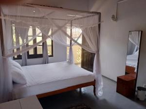 a bedroom with a canopy bed and a mirror at Sunny Seaside Haven in Talpe