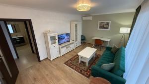 a living room with a green couch and a tv at Coresi Long Stay Apartment in Braşov
