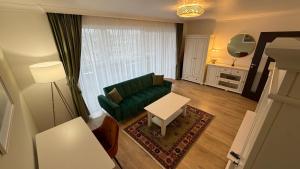 a living room with a green couch and a table at Coresi Long Stay Apartment in Braşov