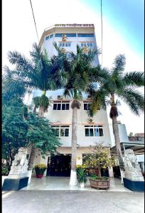 a building with palm trees in front of it at Trường Ngọc Hotel in Buon Ma Thuot