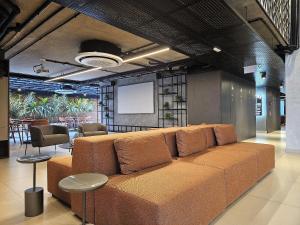 a large brown couch in a room with a screen at Lindo Studio no Coração de Tambaú in João Pessoa