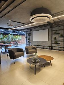 a room with chairs and a table and a screen at Lindo Studio no Coração de Tambaú in João Pessoa +29 photos